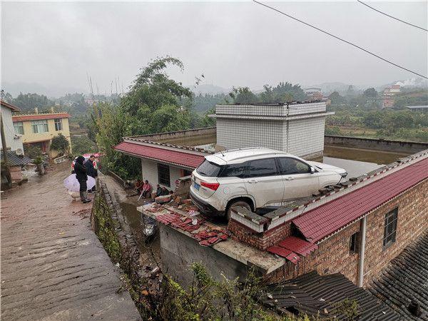 四川宜宾一轿车冲出公路开上居民房顶